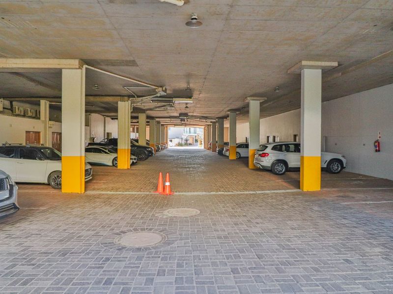 A covered parking garage featuring concrete ceilings, structural support columns, and durable paved flooring.