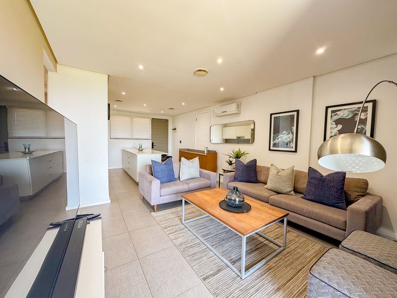 Spacious open-plan living area featuring tiled floors, recessed lighting, and a modern kitchen island, creating a bright and functional living space.