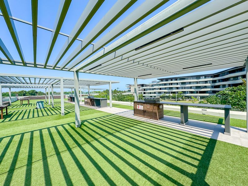 Spacious rooftop terrace featuring a modern pergola, artificial turf, and built-in braai facilities, perfect for outdoor entertaining.