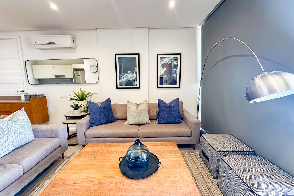 A well-maintained living room featuring recessed downlighting, a split-system air conditioner, and a modern accent wall.