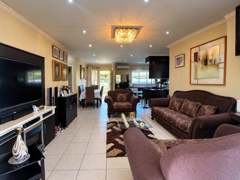 Spacious open-plan living and dining area featuring tiled floors, decorative cornices, and a modern kitchen with island, creating a functional and connected living space.