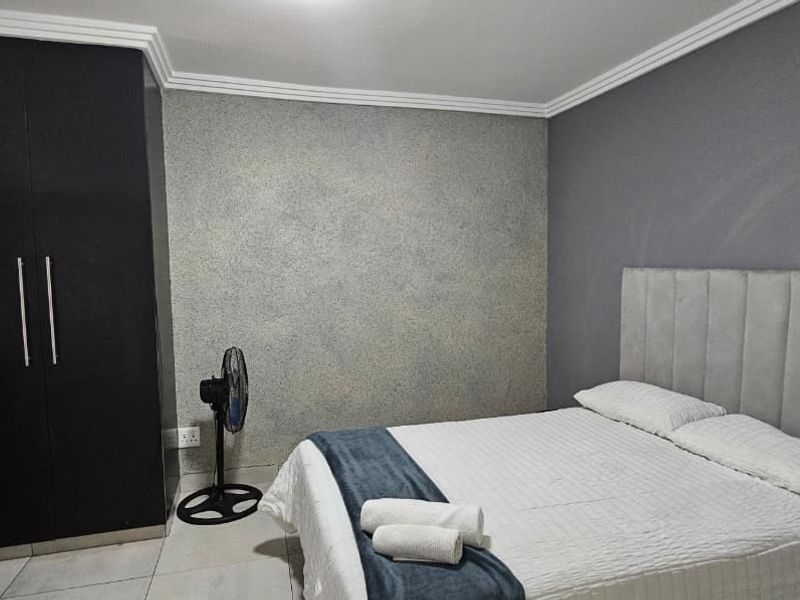 A well-maintained bedroom featuring tiled flooring, crown molding, and a built-in wardrobe with a modern dark finish.