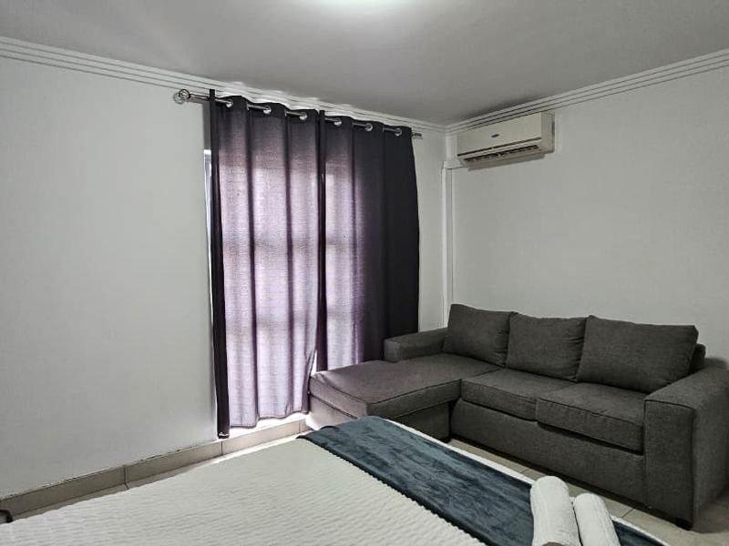 A bedroom featuring tiled flooring, crown molding, and a wall-mounted air conditioning unit, providing a functional and comfortable living space.