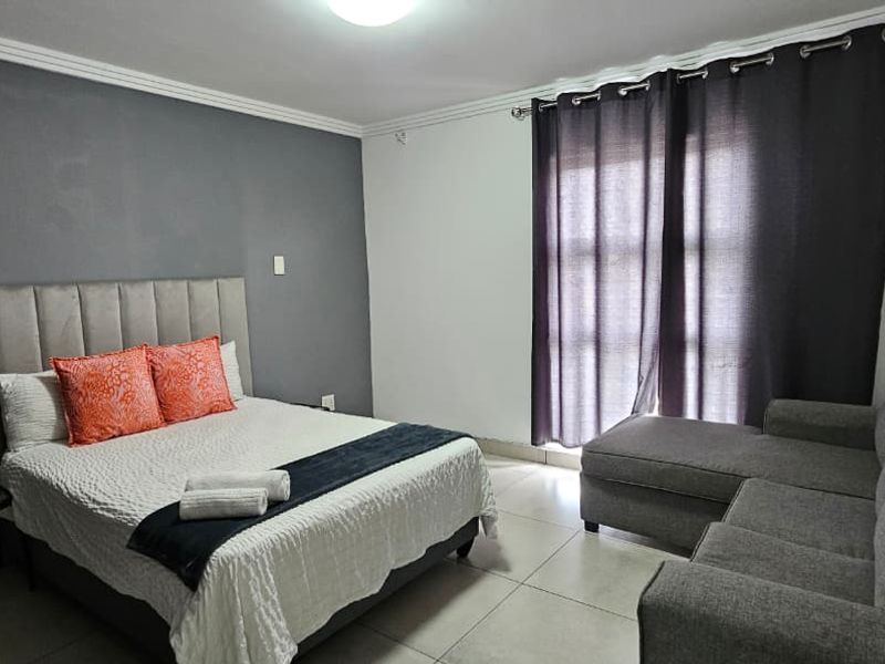 A well-maintained bedroom featuring tiled flooring, a feature wall, and a sliding door providing access to the exterior.
