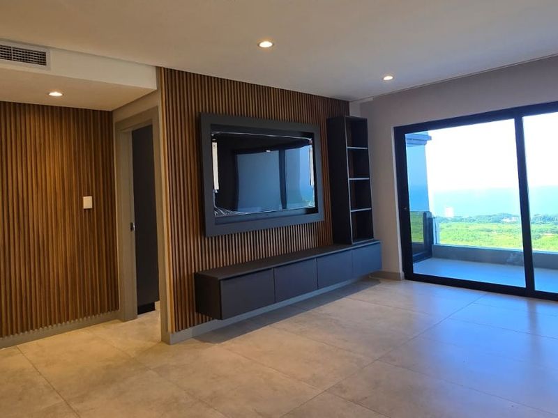 Modern living area featuring sophisticated timber slat wall paneling, built-in media cabinetry, large format floor tiles, and expansive sliding doors leading to a balcony.