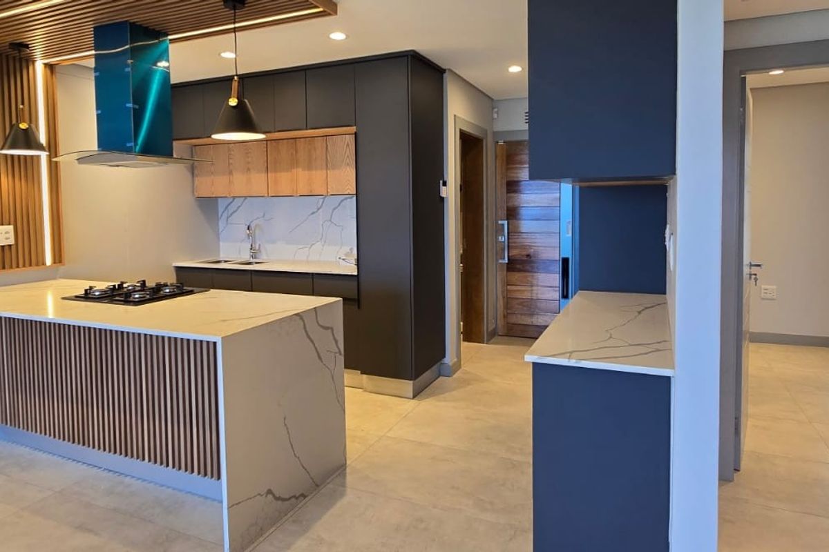 Modern kitchen featuring a stone-topped island with built-in hob, sleek cabinetry, and elegant slatted wood accents, creating a sophisticated and functional culinary space.