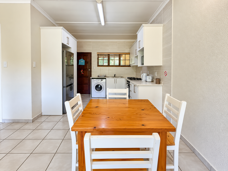 Open plan kitchen and dining area featuring tiled flooring, white cabinetry, built-in appliances, and a tiled backsplash.