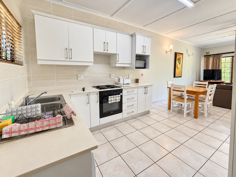 An open-plan kitchen and dining area featuring white cabinetry, tiled flooring, and a built-in oven, creating a functional and bright living space.