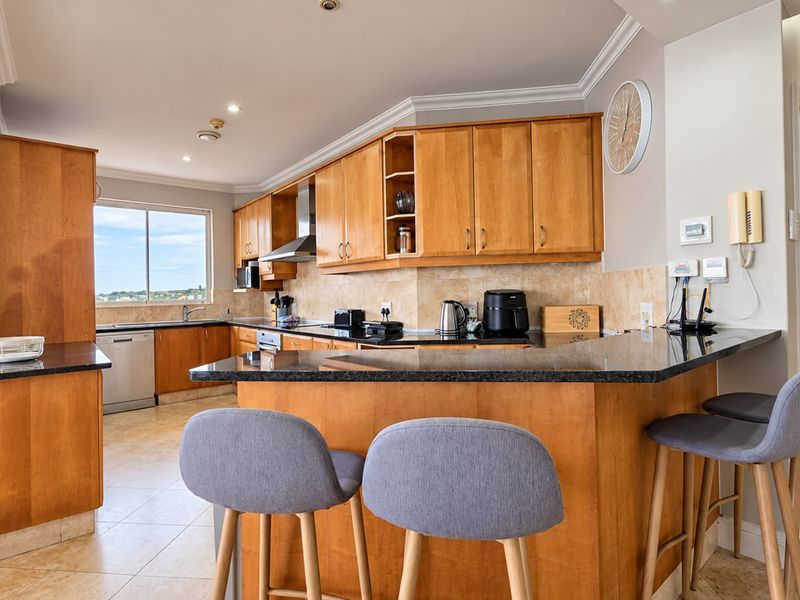 A well-maintained kitchen featuring warm wooden cabinetry, granite countertops, a breakfast bar, and integrated appliances, offering a functional and inviting cooking space.