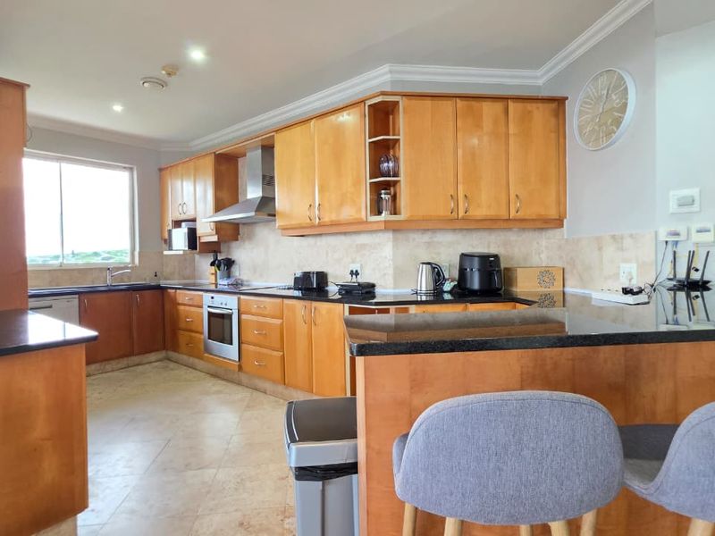 Spacious kitchen featuring warm-toned wooden cabinetry, granite countertops, a breakfast bar, and integrated stainless steel appliances, offering a functional and classic layout.