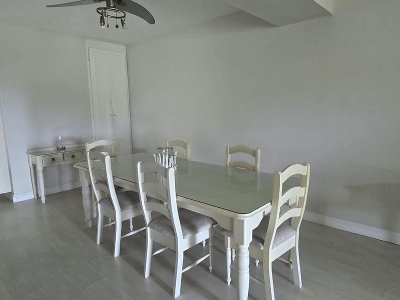 A dining area featuring a ceiling fan, neutral walls, and a built-in storage cupboard, providing a functional space for meals.