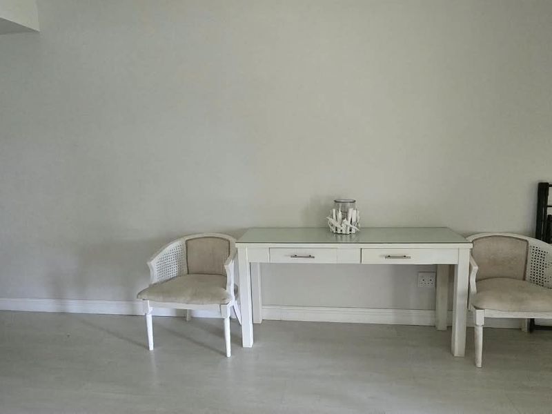 A neutrally painted living area featuring light-toned flooring, skirting boards, and a visible electrical outlet, offering a blank canvas for interior design.