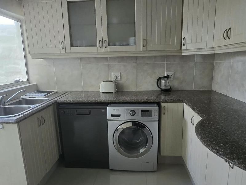 A functional kitchen featuring granite countertops, ample built-in cabinetry, a double basin sink, and dedicated space for under-counter appliances.