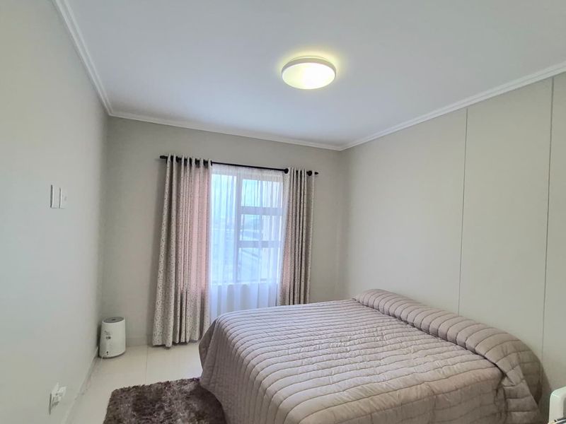 A clean and well-maintained bedroom featuring neutral wall tones, tiled flooring, and a central ceiling light fixture.