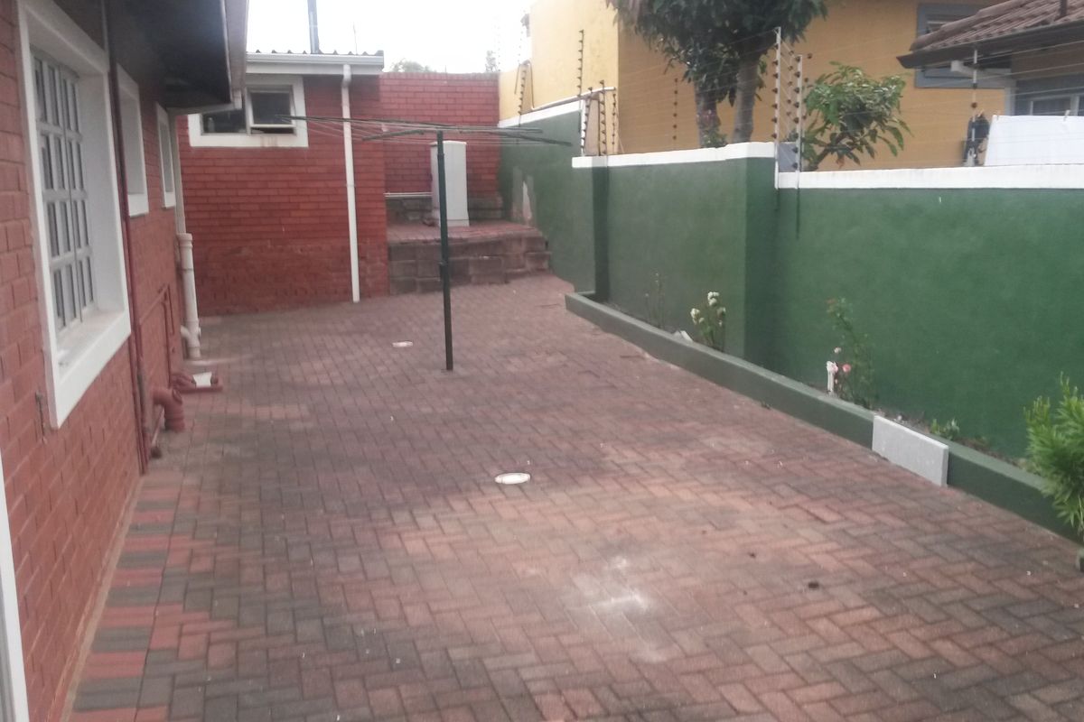 A paved rear courtyard area featuring brick boundary walls with electric fencing and a fixed washing line.