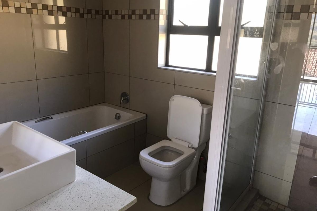 A clean, modern bathroom featuring a bathtub, separate shower enclosure, toilet, and a vessel sink set on a stone vanity countertop.