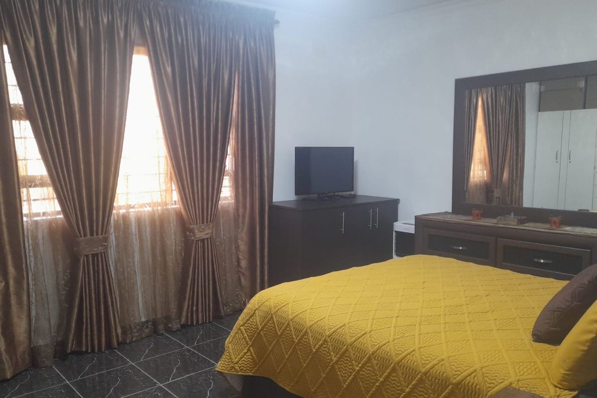 A bedroom featuring tiled flooring and window security bars, providing a functional space with natural light.