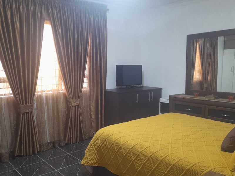 A bedroom featuring tiled flooring and window security bars, providing a functional space with natural light.