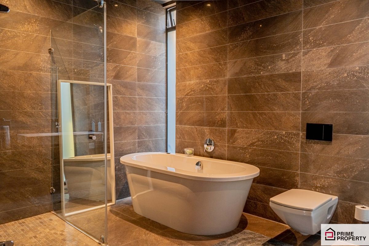 Modern bathroom featuring a freestanding bathtub, glass-enclosed shower, and wall-mounted toilet with floor-to-ceiling stone-look tiling.