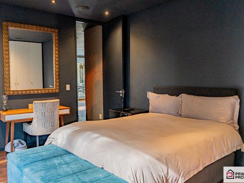 A modern, well-appointed bedroom featuring dark-toned walls, recessed ceiling lighting, and integrated door frames, creating a sophisticated and contemporary living space.