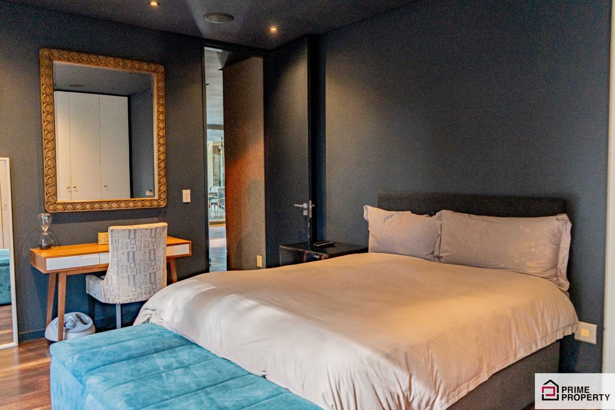 A modern, well-appointed bedroom featuring dark-toned walls, recessed ceiling lighting, and integrated door frames, creating a sophisticated and contemporary living space.