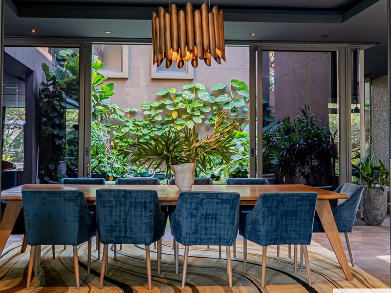 Elegant dining area featuring large sliding glass doors that open to a lush, private courtyard garden, creating a seamless indoor-outdoor living experience.