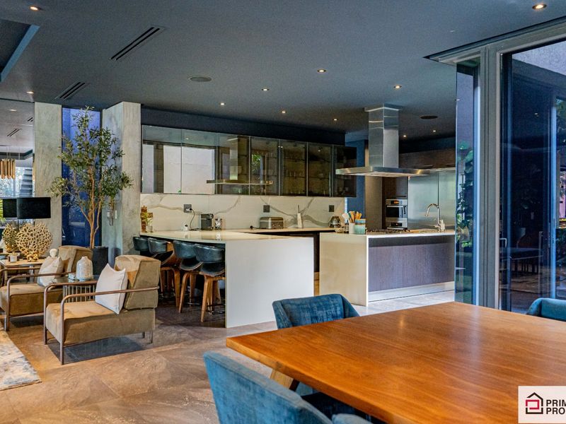 Modern open-plan living area featuring a sleek kitchen with stone countertops, integrated appliances, and recessed lighting, seamlessly flowing into the dining and lounge space.