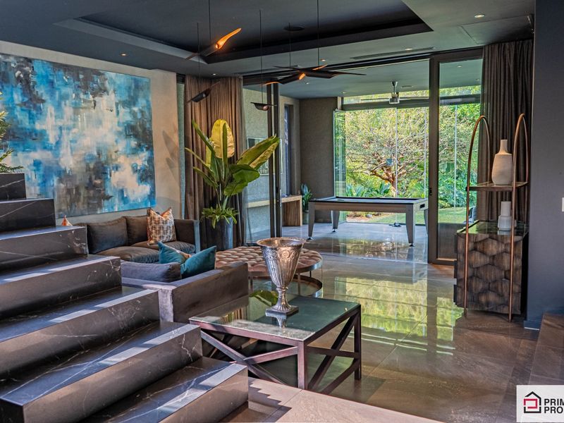 Modern open-plan living area featuring polished stone flooring, recessed ceiling lighting, and large glass sliding doors opening to a covered patio.