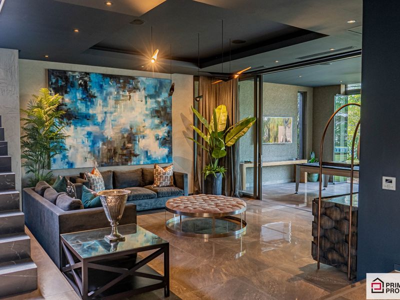 Sophisticated open-plan living area featuring high-end finishes, recessed ceiling lighting, large format floor tiles, and seamless transition to an adjacent indoor-outdoor entertainment space.