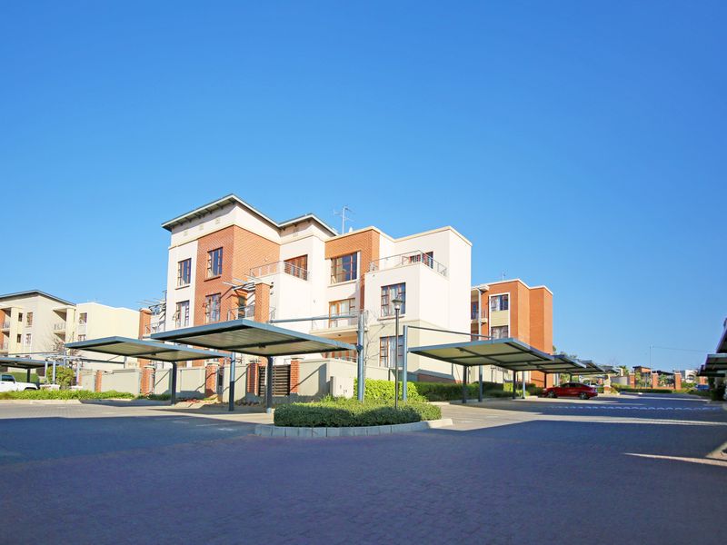 Exterior view of a modern apartment complex featuring brick and render facade, balconies, and dedicated covered parking bays.