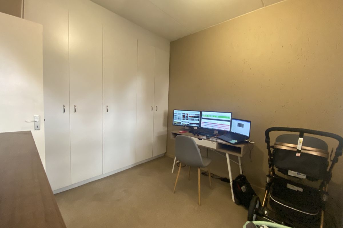 A bedroom featuring built-in cupboards and carpeted flooring, offering a functional space for a home office or sleeping area.