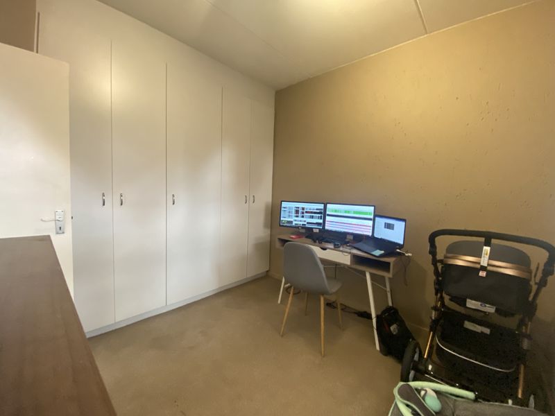A bedroom featuring built-in cupboards and carpeted flooring, offering a functional space for a home office or sleeping area.