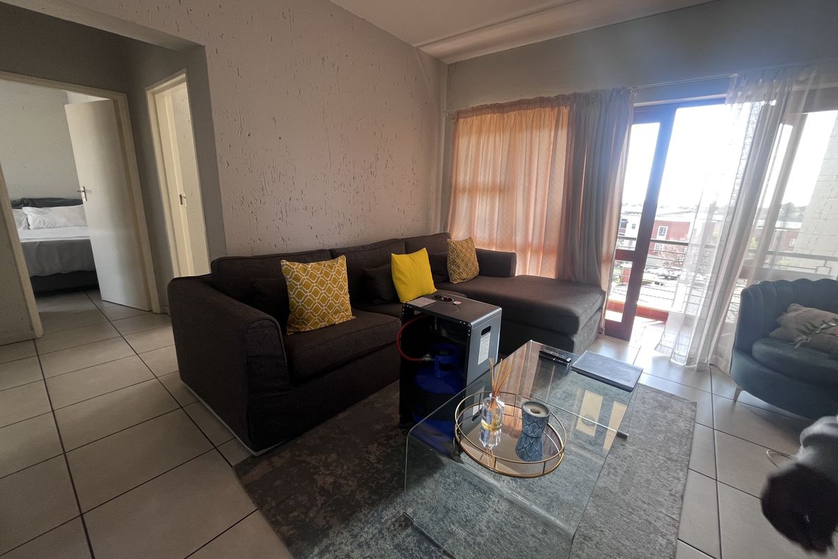 A living room featuring tiled flooring and a sliding glass door leading to a balcony, with textured wall finishes.