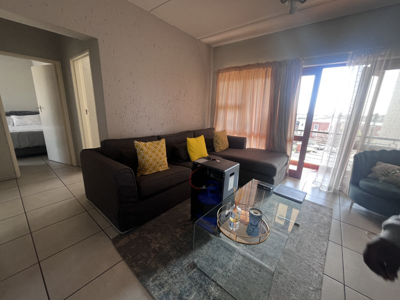 A living room featuring tiled flooring and a sliding glass door leading to a balcony, with textured wall finishes.