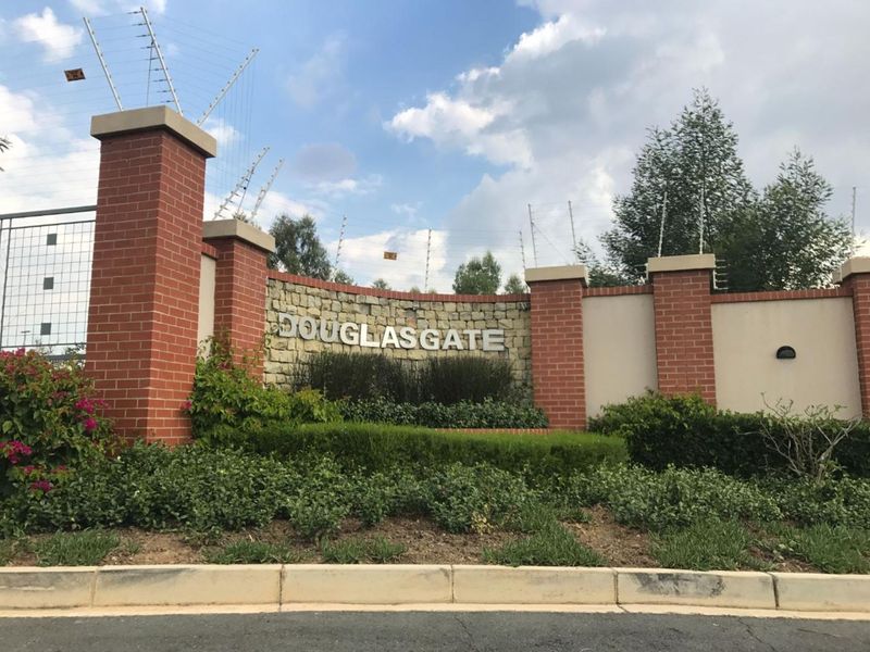 The entrance to Douglas Gate featuring brick pillars, stone cladding, and integrated security fencing.