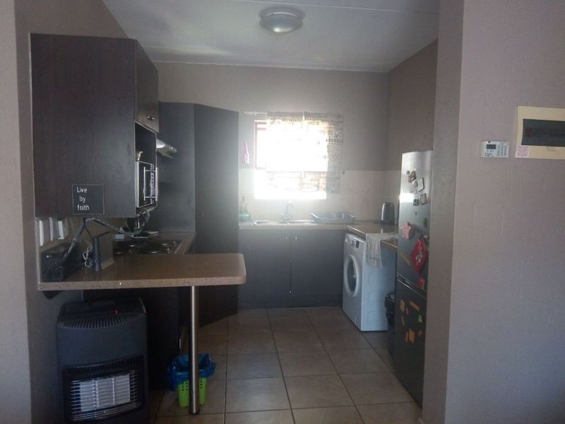 A functional kitchen featuring built-in cabinetry, laminate countertops, a stainless steel sink, and tiled flooring, offering a practical layout for daily use.
