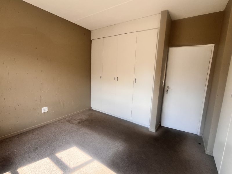 An empty bedroom featuring built-in cupboards, carpeted flooring, and neutral wall tones, offering a blank canvas for personalization.