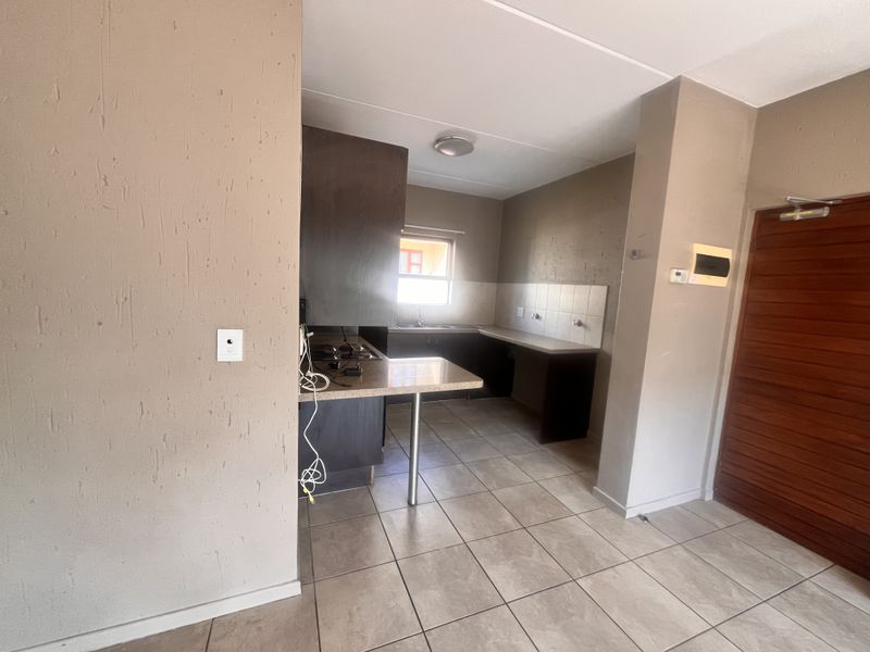 A functional kitchen featuring built-in cabinetry, laminate countertops, a hob, and tiled flooring, offering a blank canvas for potential updates.
