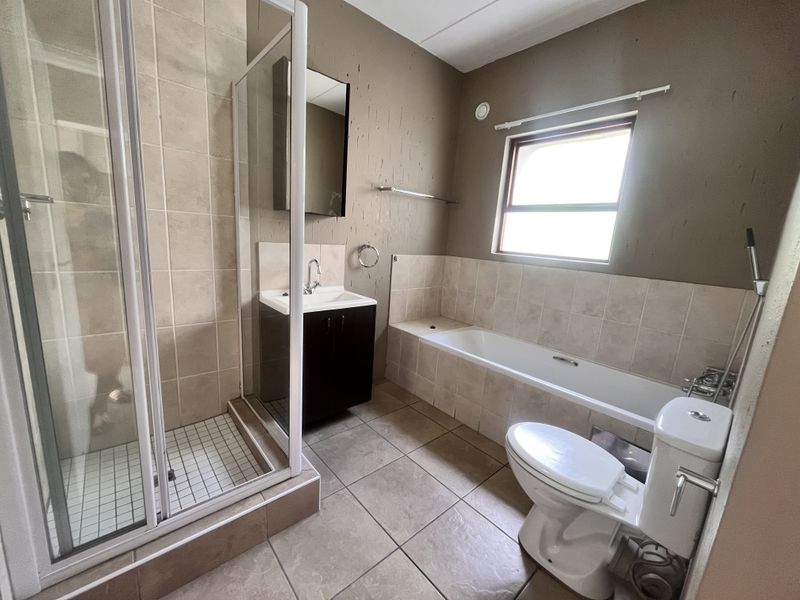 A functional bathroom featuring a separate shower enclosure, bathtub, vanity unit, and toilet, requiring cosmetic updates to the wall finishes.