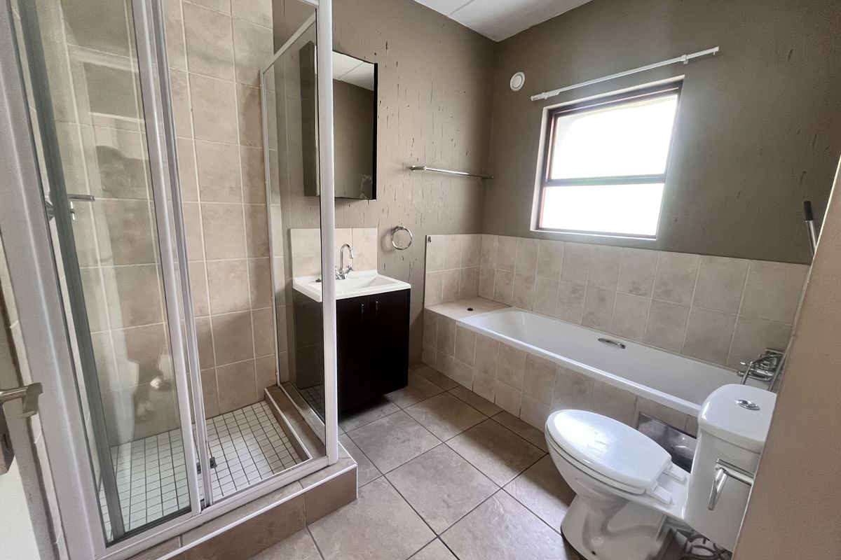 A functional bathroom featuring a separate shower enclosure, bathtub, vanity basin, and toilet with neutral floor tiling and painted walls.