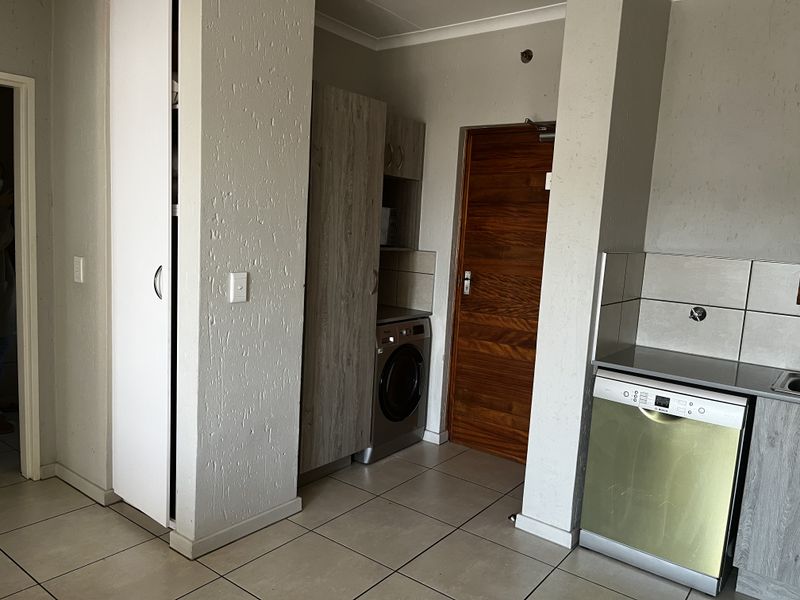 A functional kitchen area featuring tiled flooring, built-in cabinetry, and an integrated dishwasher, currently awaiting a faucet installation.