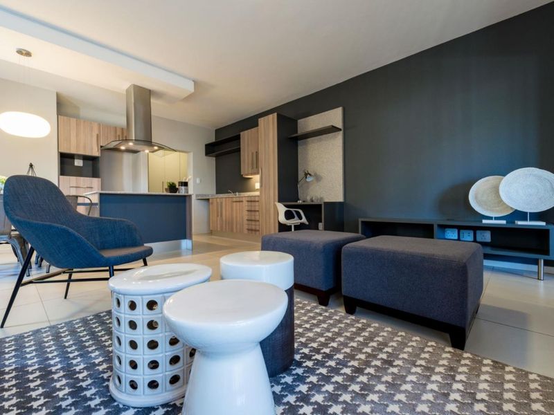 Modern open-plan living area featuring a contemporary kitchen with built-in cabinetry, an extractor fan, and a functional integrated desk space.