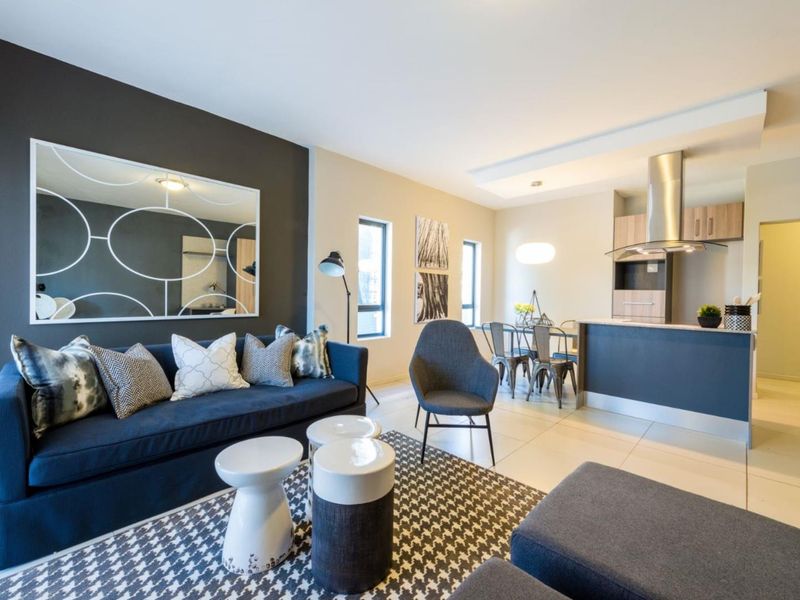 Modern open-plan living area featuring a contemporary kitchen with built-in cabinetry, an extractor fan, and sleek tiled flooring throughout the space.