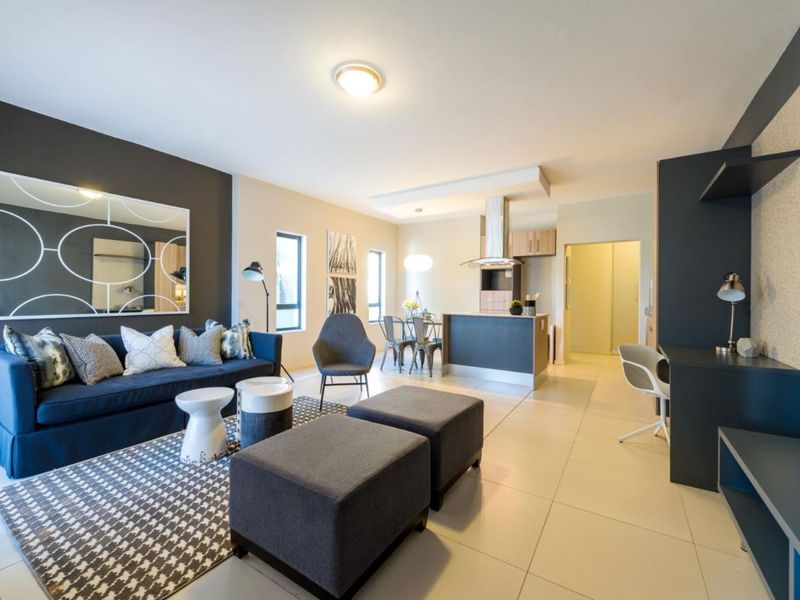 Modern open-plan living area featuring a contemporary kitchen with built-in cabinetry, extractor fan, and sleek tiled flooring throughout the combined space.