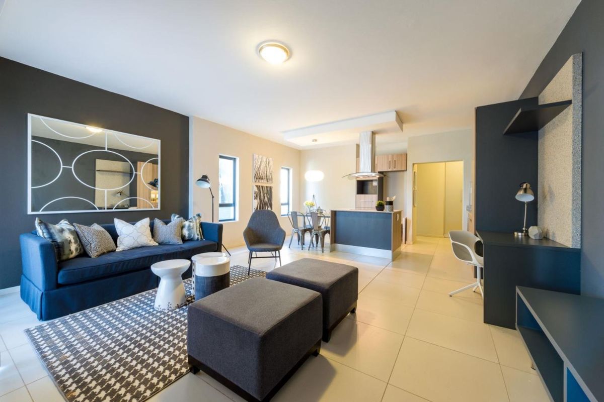 Modern open-plan living area featuring a contemporary kitchen with built-in cabinetry, extractor fan, and sleek tiled flooring throughout the combined space.