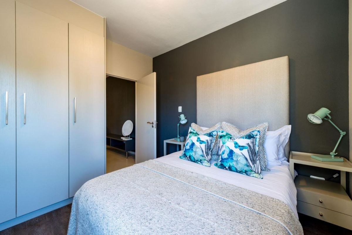 A well-maintained bedroom featuring built-in wardrobes, laminate flooring, and a modern accent wall, providing a clean and functional living space.