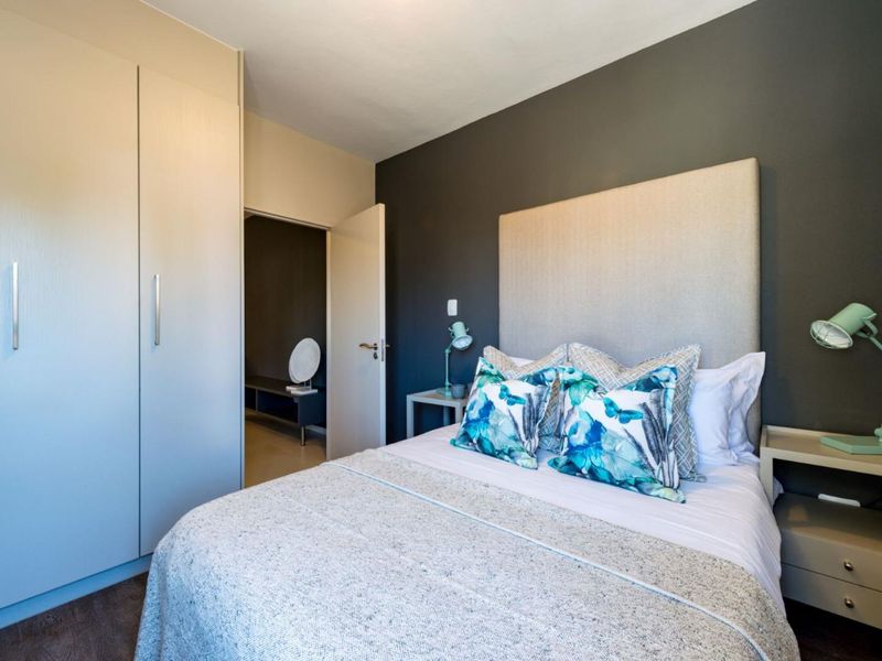 A well-maintained bedroom featuring built-in wardrobes, laminate flooring, and a modern accent wall, providing a clean and functional living space.