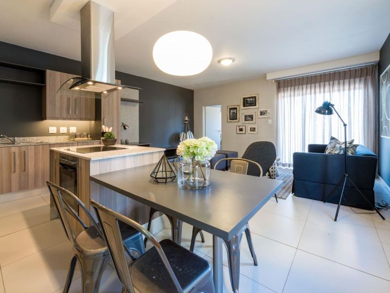 Modern open-plan living area featuring a contemporary kitchen with stone countertops, built-in appliances, and seamless flow to the lounge with sliding door access.