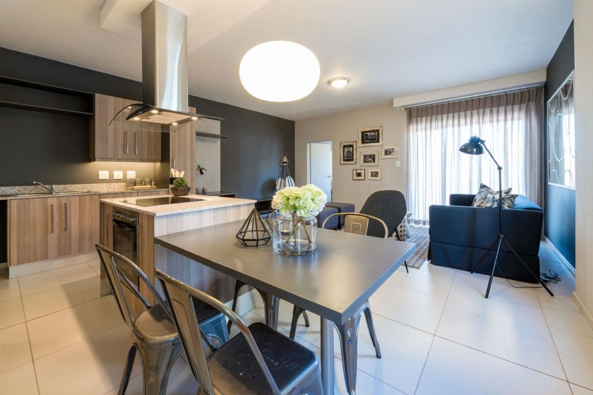 Modern open-plan living area featuring a contemporary kitchen with stone countertops, built-in appliances, and seamless flow to the lounge with sliding door access.