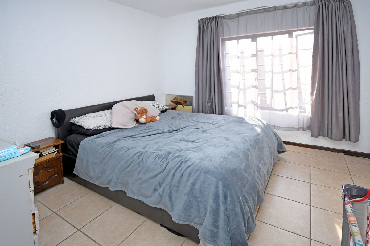 A bedroom featuring tiled flooring and a large window with curtain tracks.